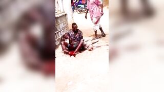 A Man Lies In The Street Being Attacked By A Man With A Machete