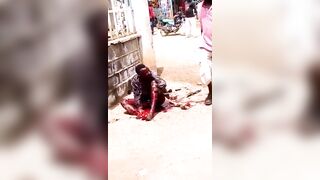 A Man Lies In The Street Being Attacked By A Man With A Machete