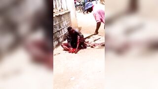 A Man Lies In The Street Being Attacked By A Man With A Machete