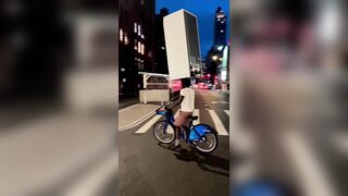 A Cyclist Carries A Refrigerator On His Head